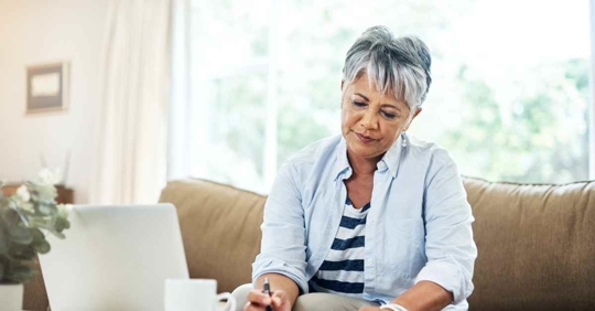 An older woman reviewing documents at her couch
