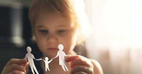 A child holding a paper cut out of two parents and a child