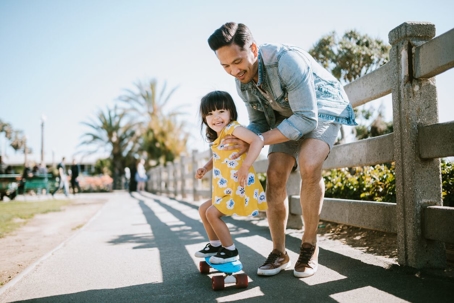 Father and daughter playing outside on skateboard