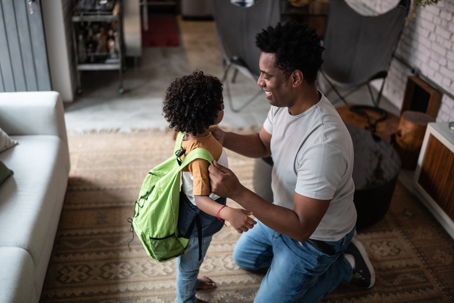 father helping son put on backpack
