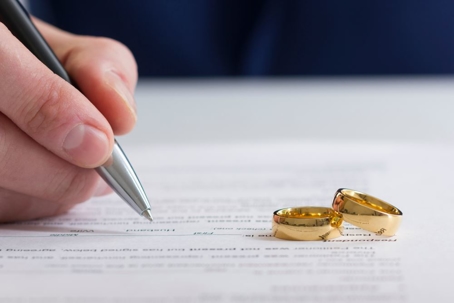 Legal documents with wedding rings on desk